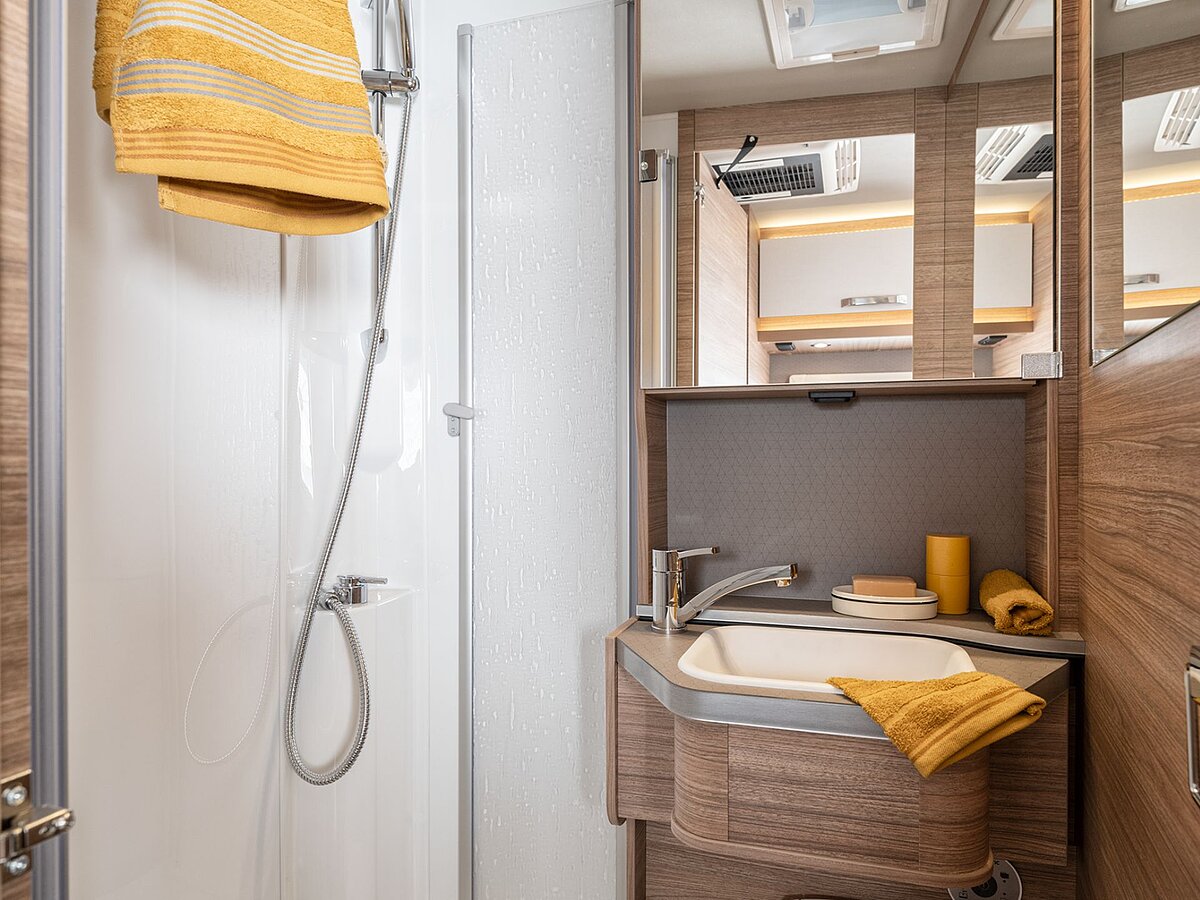 Badezimmer in einem Wohnmobil mit Handtüchern über der Duschtür und am Waschbecken.