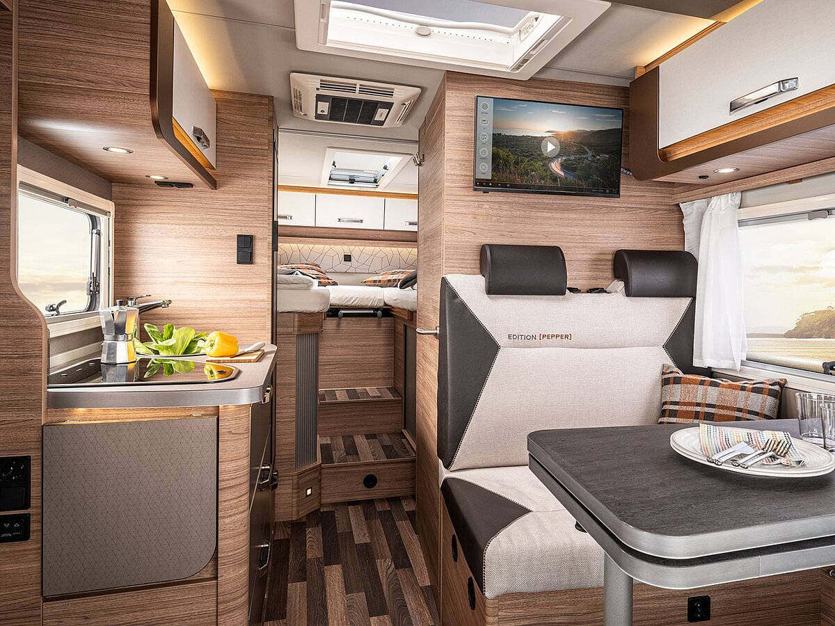 Blick in den Innenraum eines Wohnmobils mit Sitzgruppe, Küche und Schlafplatz