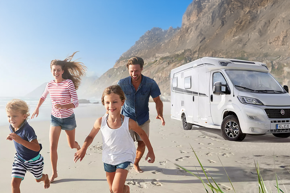 Eine Familie mit zwei Kindern hat ihr Wohnmobil am Strand geparkt und rennt am Meer entlang.